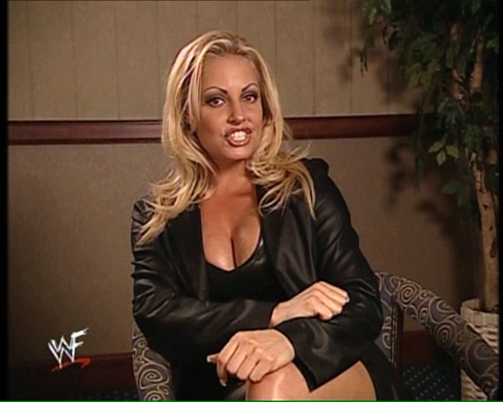 Trish Stratus - black leather, cleavage, short skirt, sitting legs crossed.